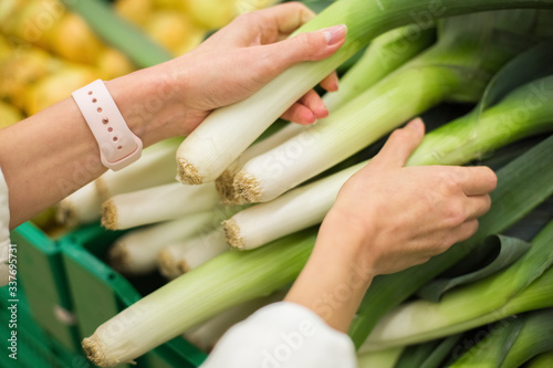 Woman holding and chooses fresh leek in grocery store