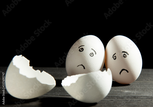 two sad eggs look at a broken egg on a black background
