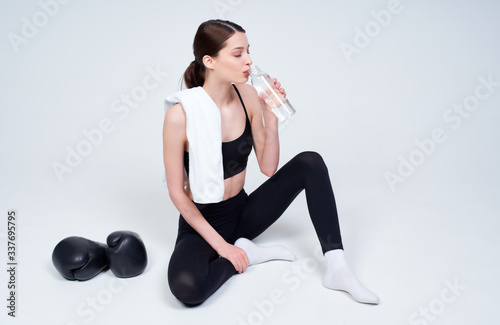 Sports fitness girl resting after a workout and drinks water.