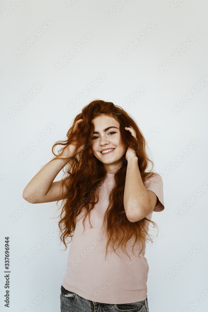 joyful red-haired girl smiling holds her hair on a white background joyful red-haired girl smiling holds her hair on a white background