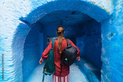girl traveler from the back. standing with backpacks on a background of the blue city of chefchaouen © nelen.ru