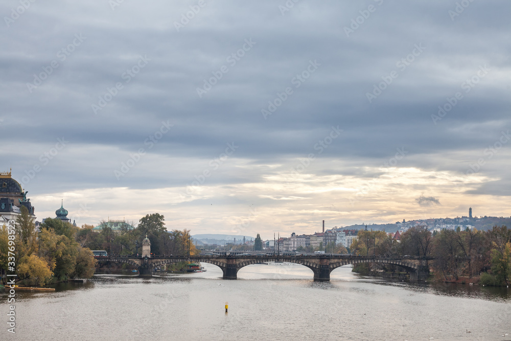 Panorama of Prague, Czech Republic, seen from the Vltava river, also called Moldau, with a focus on Most Legii, or Legion Most, one of the landmarks of the city, during a cloudy sunset in autumn