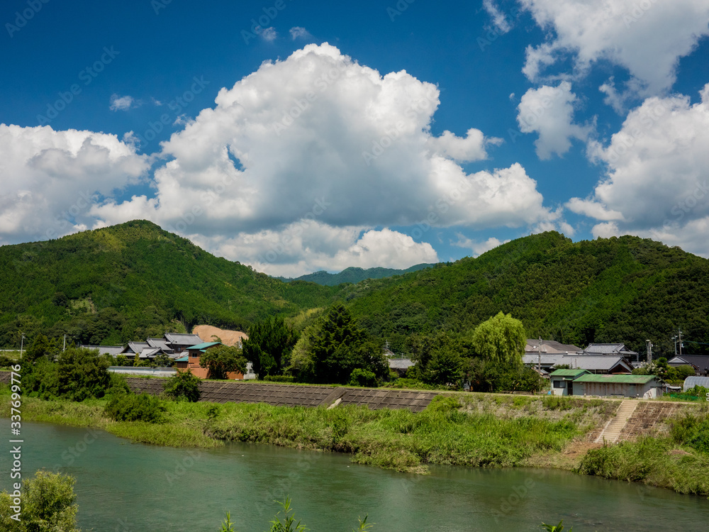 青い空と白い雲と川と山のある日本の里山の風景。
