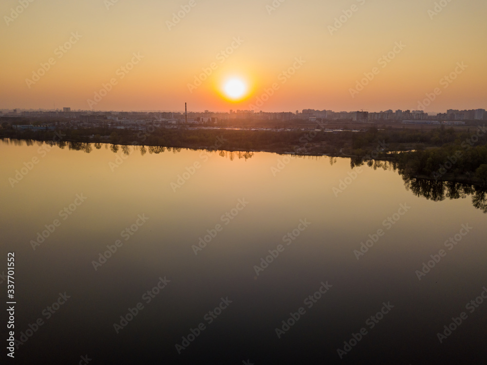 Sunset over the lake in the city. Aerial drone view.