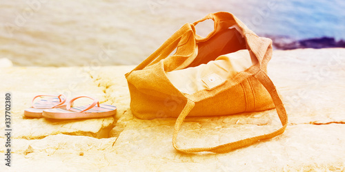 Beach bag and sandals on a stone seashore