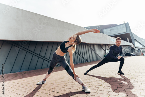 Beautiful fitness sportgirl and sportmen with fit body in sportswear exercising outdoors, stretching, yoga, outdoor sports, urban style.