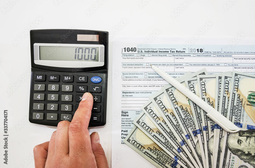 hand prints on a calculator against the background of tax forms 1040 and dollars. Tax concept. hand prints on a calculator against the background of tax forms 1040 and dollars. Tax concept.