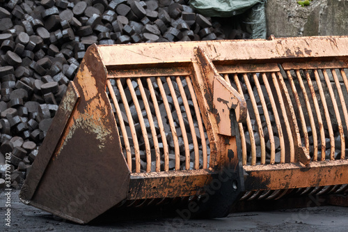 excavator shovel in front of coal mountain