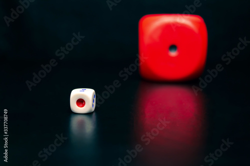 Big red dice next to a small white dice