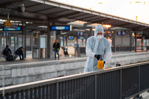 Ein Mann in einem Schutzanzug desinfiziert an einem Bahnhof ein Geländer, Kampf gegen die Ausbreitung des Coronavirus 