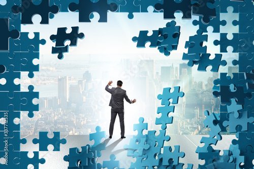 Businessman breaking the wall of jigsaw puzzle