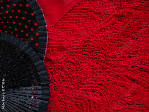 Black open fans for flamenco dancing on a red Spanish shawl. Background for a flamenco school or dance website or postcard. Mockup for the designer. Bright background in Spanish style with copy space