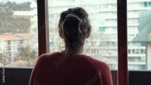 Girl looking out the window while locked up at home during confinement due to coronavirus photo