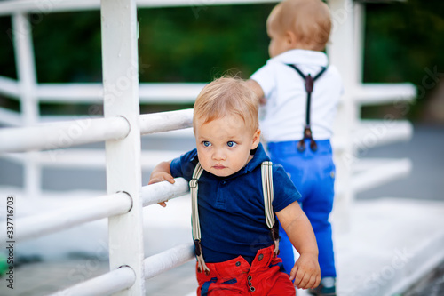 portrait of a boy with blond hair and blue eyes European appearance. A boy in a polo and suspenders on the street © Valkirencia