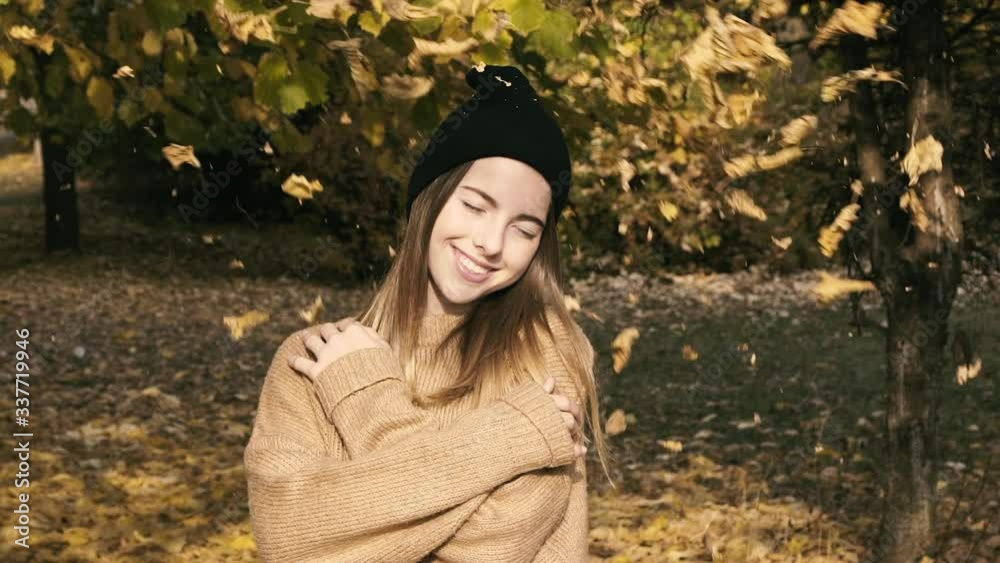 Young girl smiling at camera under falling leaves in autumn park. Young girl smiling at camera under falling leaves in autumn park.