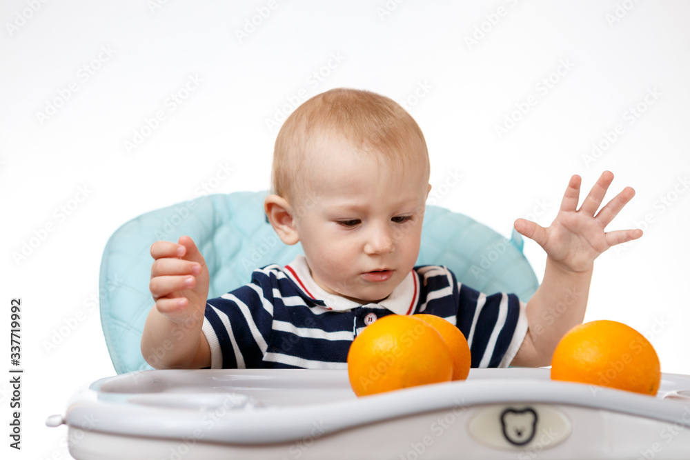 Cheerful little boy is eating oranges on a white background Cheerful little boy is eating oranges on a white background
