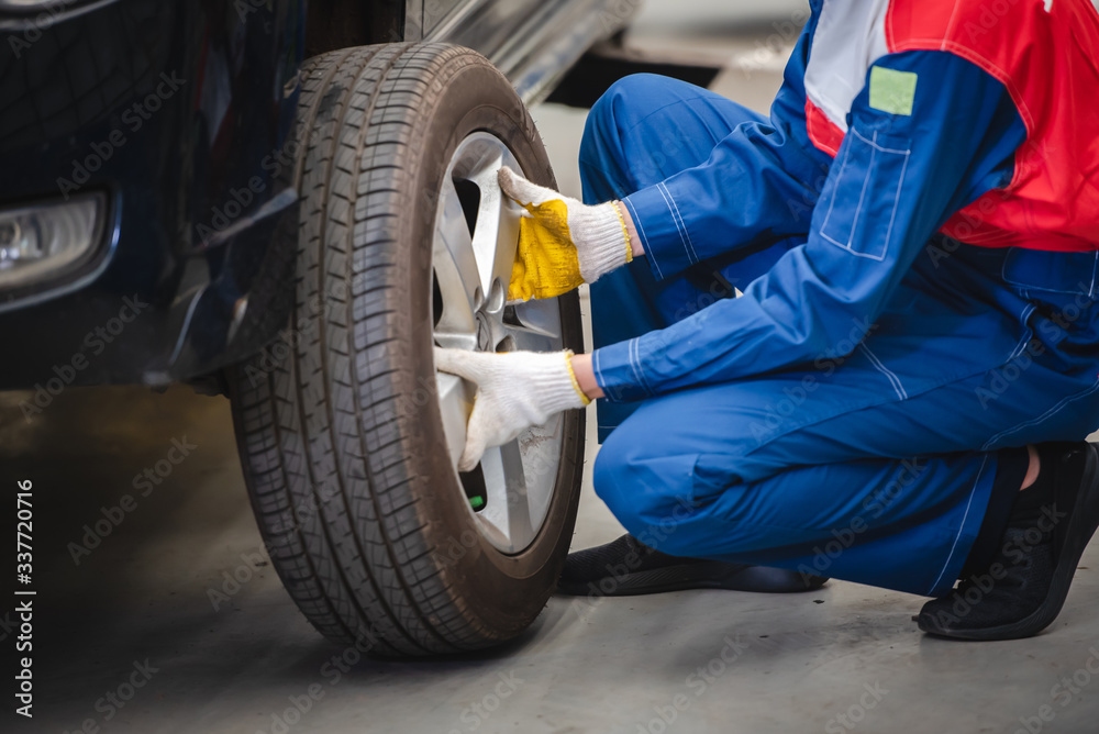 Asian car mechanic is removing the wheel and checking the brakes and suspension in the car service with a forklift. Repair and maintenance center Asian car mechanic is removing the wheel and checking the brakes and suspension in the car service with a forklift. Repair and maintenance center