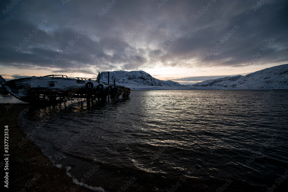 abandoned, already rotten skeletons of ships lying on the coast of the Arctic ocean against the background of a pink sunset abandoned, already rotten skeletons of ships lying on the coast of the Arctic ocean against the background of a pink sunset