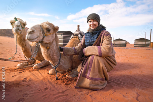 Canvas-taulu Young woman in traditional Bedouin coat - bisht - and headscarf crouching next t