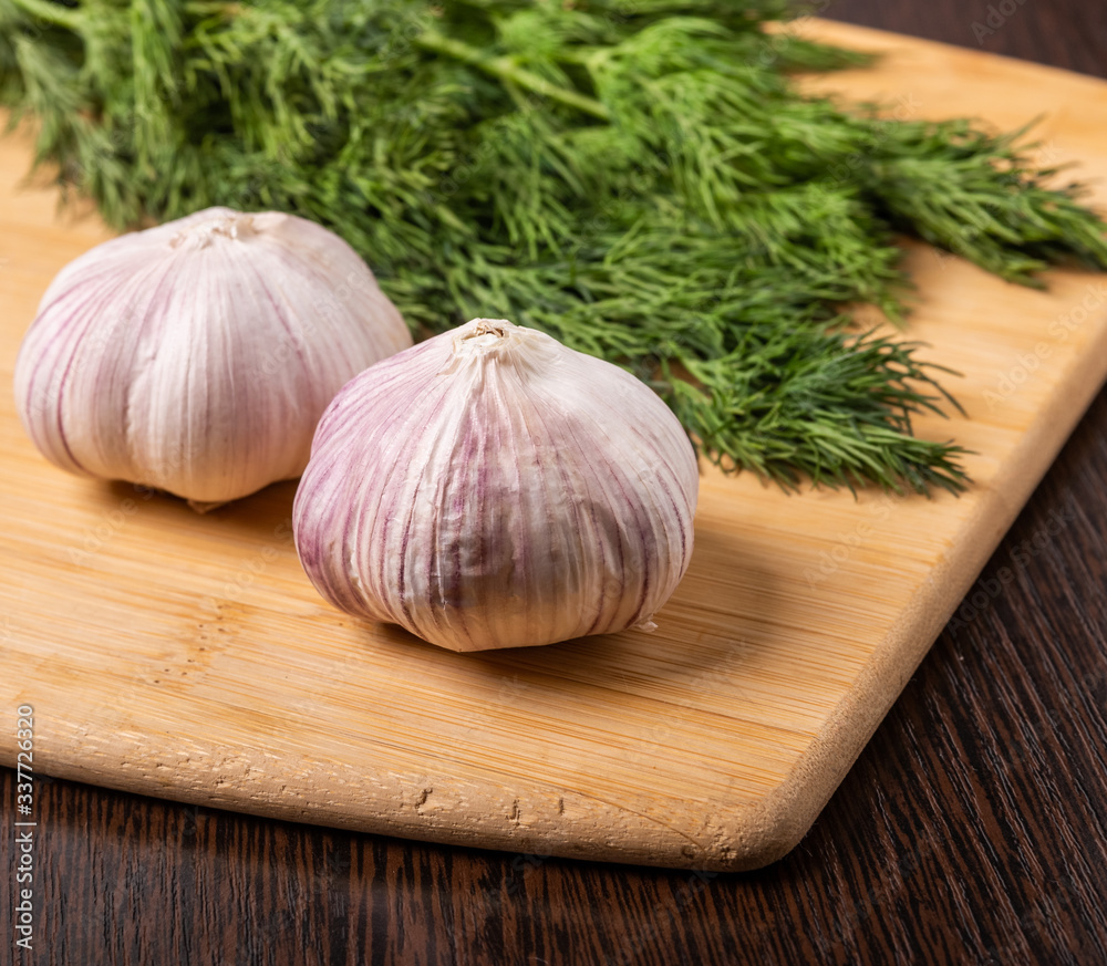 Garlic and dill are on the cutting Board. Garlic and dill are on the cutting Board.