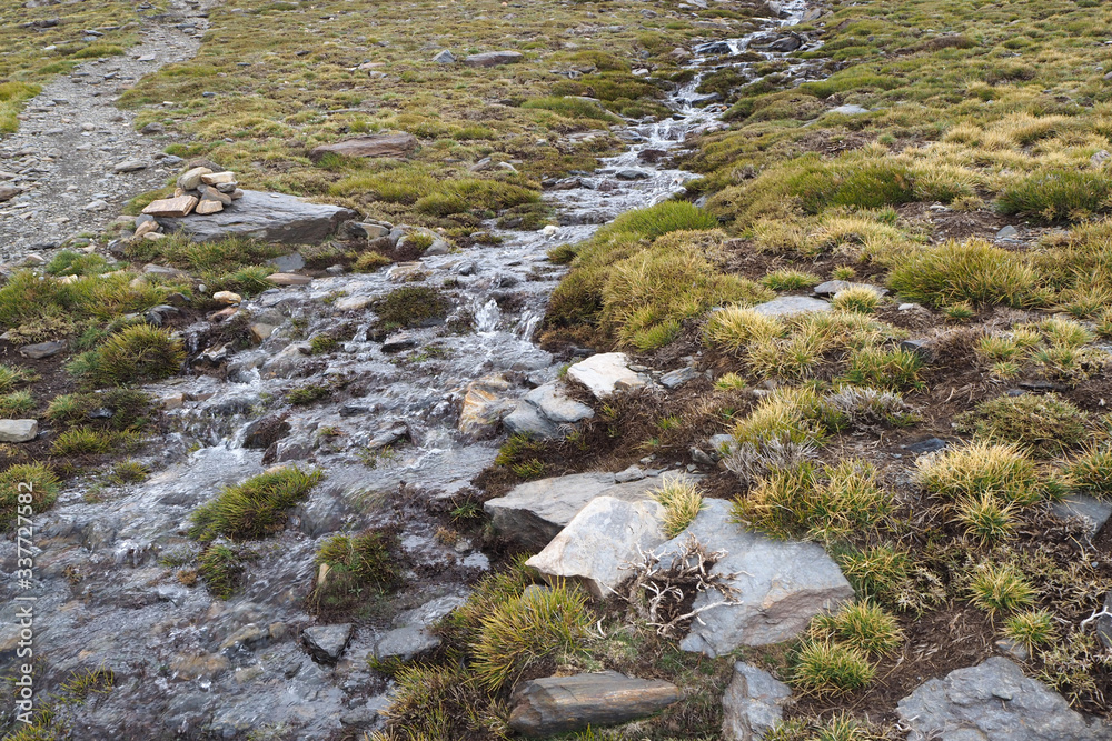 The mountain landscape with the small mountain river, the green grass and the stony path on the cloudy day. The mountain landscape with the small mountain river, the green grass and the stony path on the cloudy day.