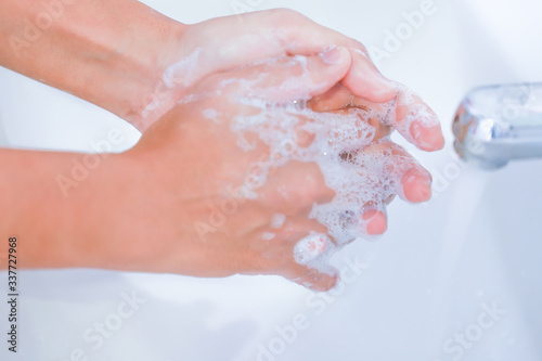 Close-up of young women washing hands with soap rubbing fingers and skin under faucet water flows on white basin for pandemic prevention Coronavirus, Covid-19