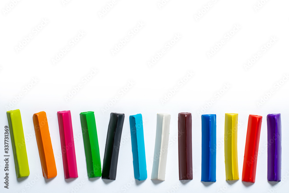 multi-colored plasticine sticks laid out in parallel on a white background. isolate. place for text