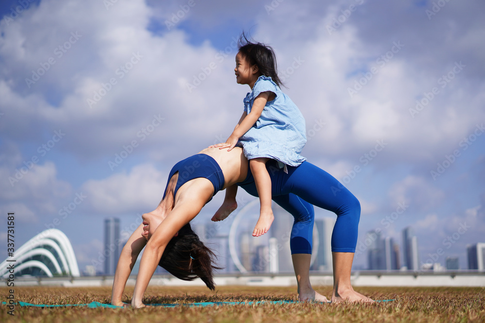 Asian chinese female yogi playing with daughter outdoors under the sun