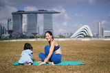 Asian chinese female yogi playing with daughter outdoors under the sun