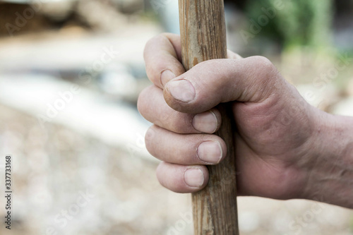 hand of a senior farmer lies on a pole of an agricultural implement, weathered hand with wrinkles, fresh food concept