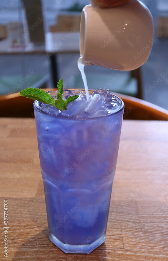 Pitcher of Fresh Lime Juice Pouring into Iced Butterfly Pea Flower Tea Pitcher of Fresh Lime Juice Pouring into Iced Butterfly Pea Flower Tea