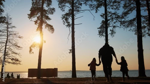 father with two children run away at sunset to the river photo