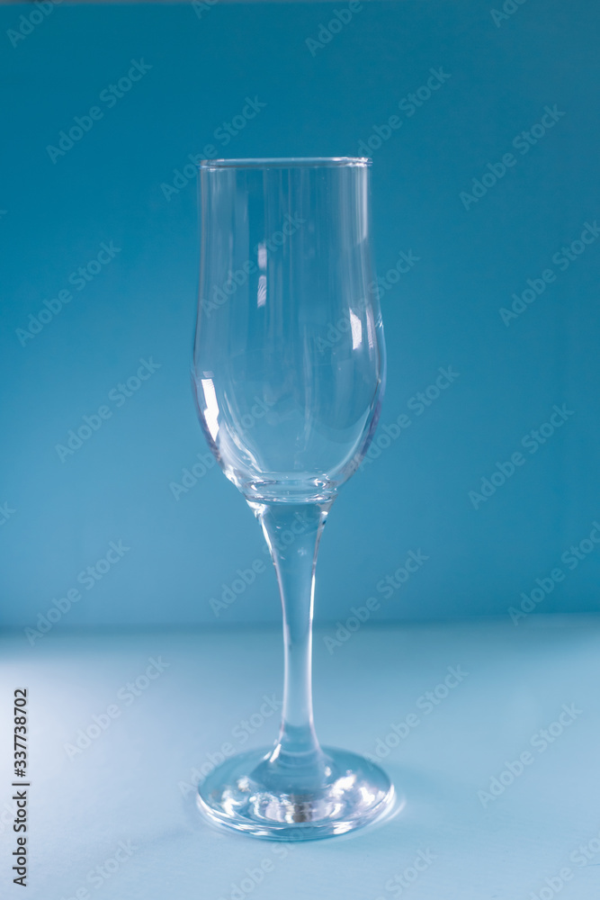 Empty glass on a blue background.Tableware for alcohol.A glass for champagne and wine. Empty glass on a blue background.Tableware for alcohol.A glass for champagne and wine.