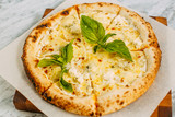 Italian pizza with mozzarella cheese and basil on a marble table