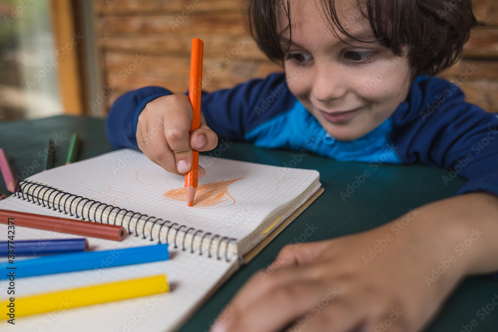 The child draws with pencils in a notebook, The boy drew a heart. The child draws with pencils in a notebook, The boy drew a heart.