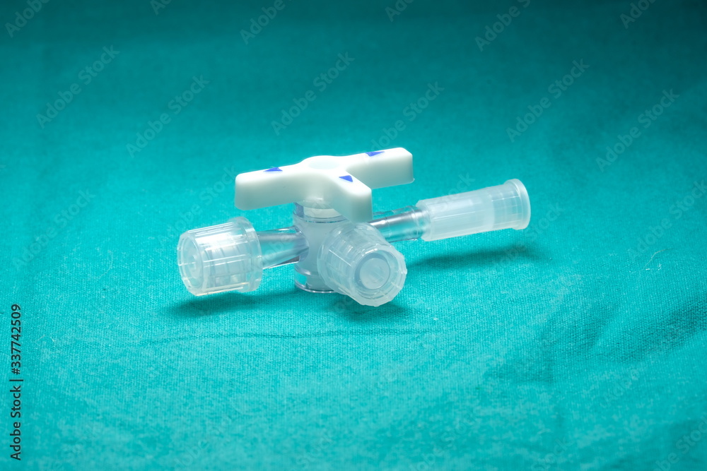 Three way stopcock with luer slip For medical purposes On a green cloth Three way stopcock with luer slip For medical purposes On a green cloth
