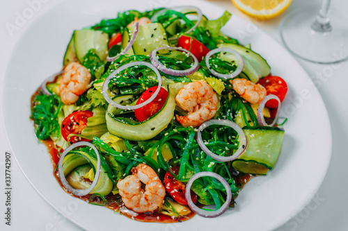 fresh vegetable salad with shrimp, with lemon and wine on a white background
