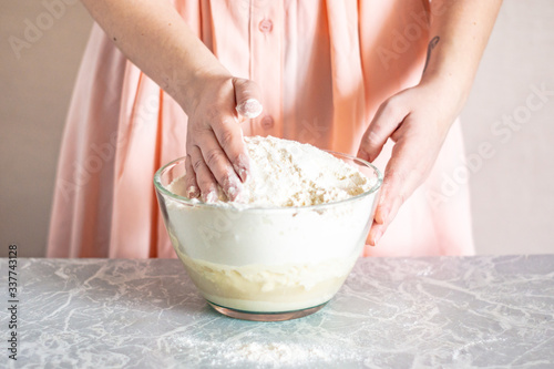 A woman mixes ingredients with her hands, the process of kneading the dough.