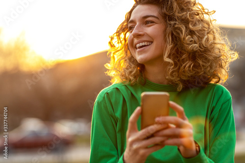 Young hipster woman using smartphone at sunset
