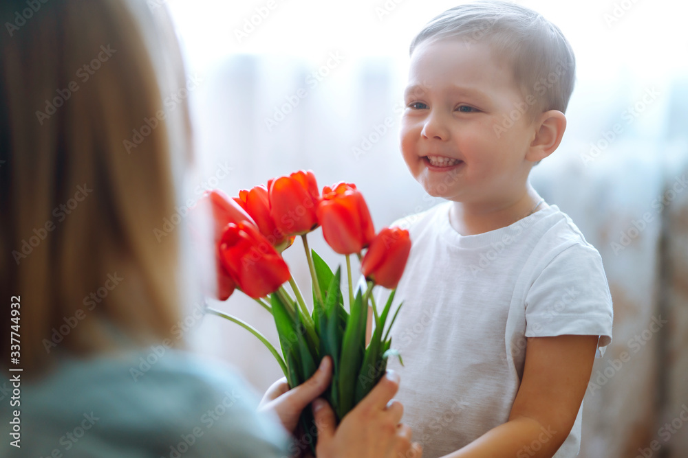 Little son congratulates mother and gives a bouquet of flowers tulips. Happy mother's day. Family holiday and togetherness. Little son congratulates mother and gives a bouquet of flowers tulips. Happy mother's day. Family holiday and togetherness.