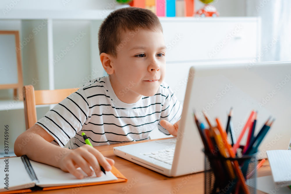 Distance learning online education. A schoolboy boy studies at home and does school homework. A home distance learning