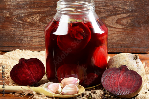 pieces of garlic, beets, spices next to the jar with pickled beets in the jar