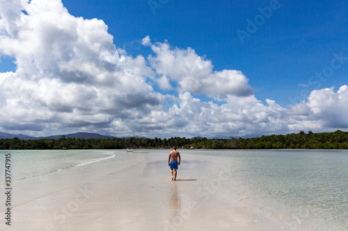 A young man takes a walk on a sand dune between two waters in a Puerto Princesa beach, Palawan, Philippines photo