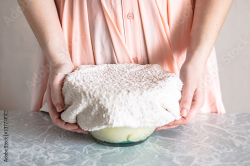 The woman covers the dough in a bowl with a towel.
