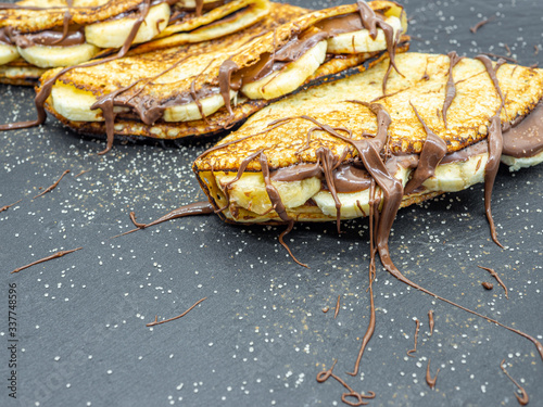 crepes with banana slices and chocolate served on slate