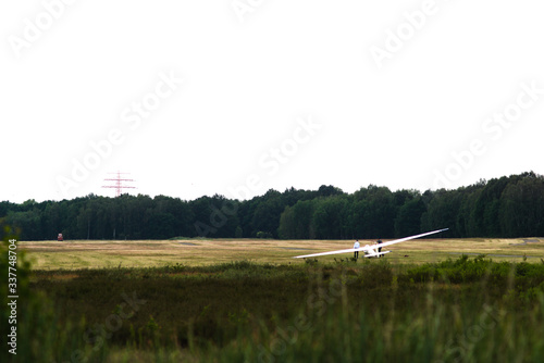Segelflugzeug vor dem Start an einer Seilwinde vor Bäumen und Strommast 