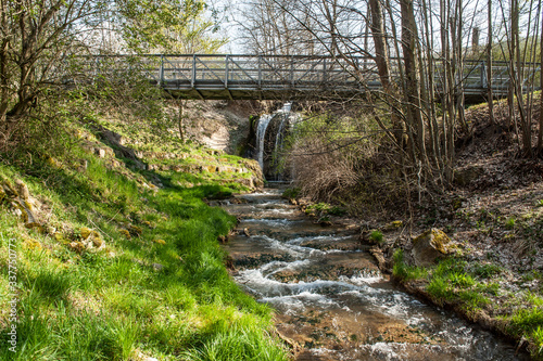 Fluss mit Wasserfall hinter Br  cke mit Eisengel  nder