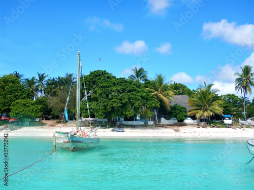 Tropical island with boat in turquoise water and palm trees