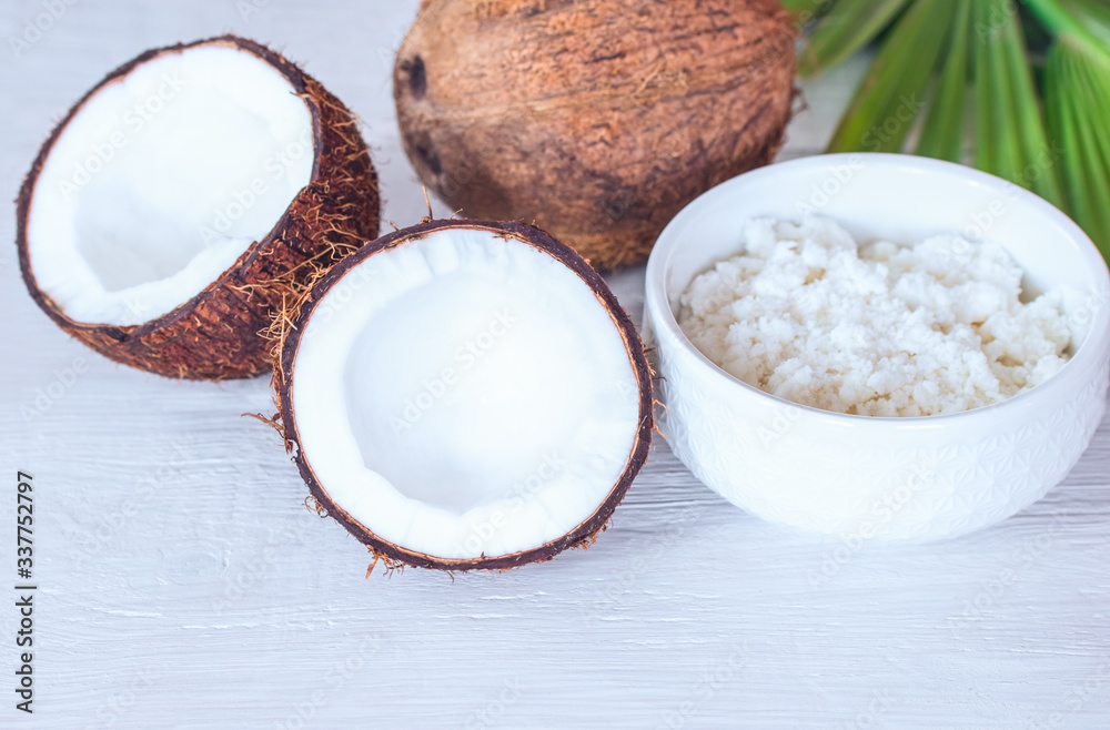 halves of a coconut, a whole coconut and a bowl of coconut paste close-up. background with fresh coconuts and coconut paste. halves of a coconut, a whole coconut and a bowl of coconut paste close-up. background with fresh coconuts and coconut paste.