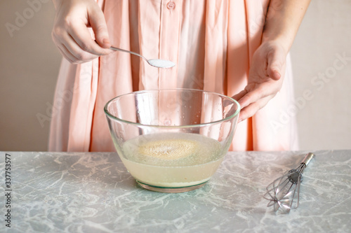 A woman pours salt into a bowl, the process of kneading the dough.